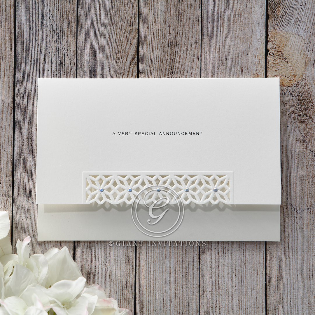 Matte white card with die cut flap cover and jeweled center, pre-stamped with silver foiled lettering, enclosed in a complimentary envelope with metallic lining
