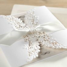 Knotted white satin lace wrapped around a matte white card with floral and leaf lasercut detail, ivory insert card