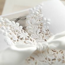 Charming white lasercut details in leaf pattern, enclosing an inner card with black ink printing, knotted lace wrapped around