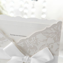 White insert card with embossed border, white pocket invite with floral design, smooth satin ribbon and lace