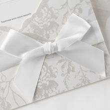 Classic white ribbon wrapped around a pocket invite with silver floral designs, inner card with embossed frame