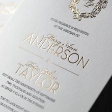 Lustrous gold foiled names and emblem with black ink calligraphic block letters, printed on a lightly textured card