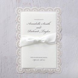 Luxurious textured ivory coloured card wrapped with a white satin bow, attached to a sturdy white coloured backing card with floral die cut borders
