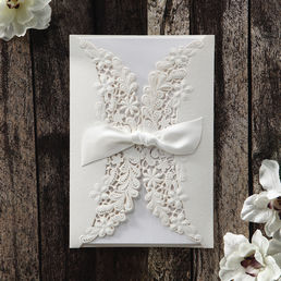 Bright white trifold card printed in calligraphic fonts inserted in a gorgeous gatefold pocket with laser cut flap adorned with a ribbon
