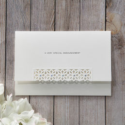 Matte white card with die cut flap cover and jeweled center, pre-stamped with silver foiled lettering, enclosed in a complimentary envelope with metallic lining
