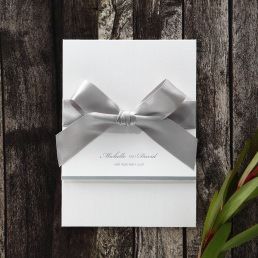 Sophisticated trifold card with pre-stamped silver foiled letters, enclosing an embossed insert card wrapped with a sparkling silver ribbon
