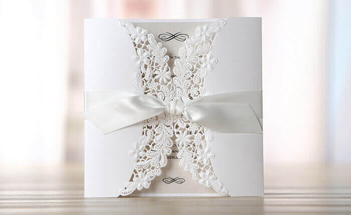 An immaculately white floral laser cut pearlised wedding card with sateen ribbon